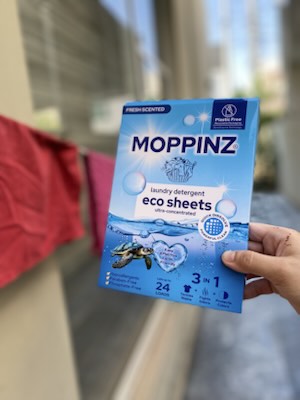 A customer holding the 24-load Moppinz eco sheets box outdoors beside a washing line of drying clothes